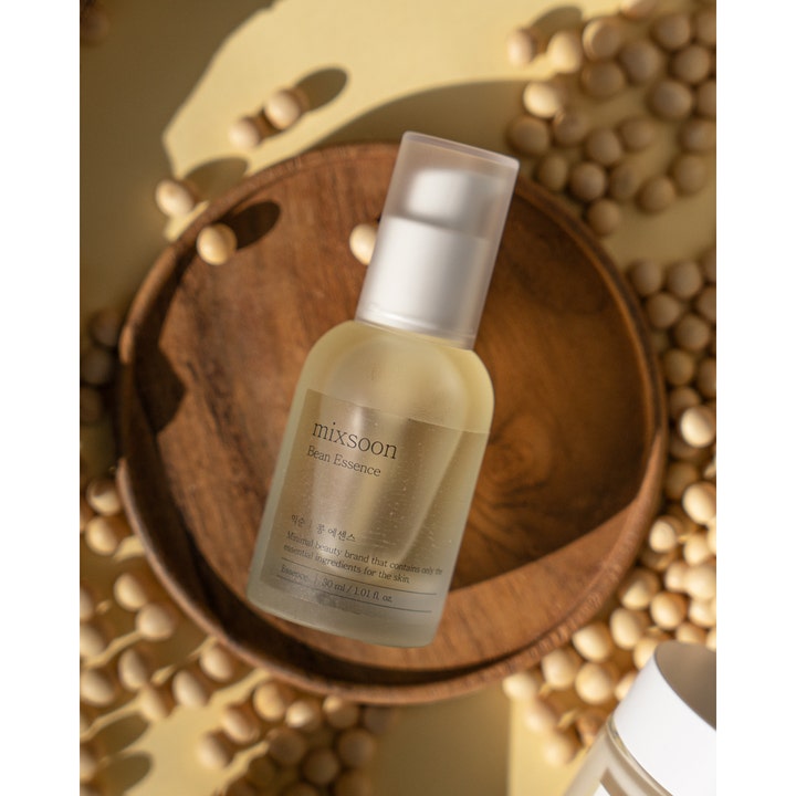 Mixsoon Bean Essence 30 ml återfuktande bön essens i frostad pumpflaska omgiven av naturliga sojabönor på träfat