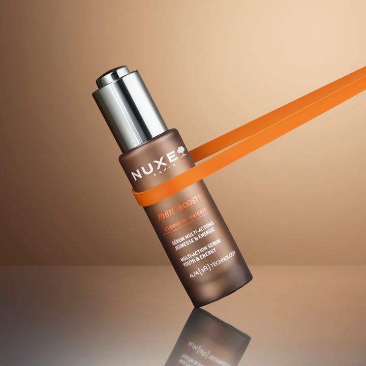 Nuxe Men Multi Action Serum 30 ml ger huden energi i en brun glasflaska med silverkork och orange detaljer.