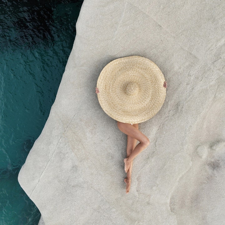 KORRES Yoghurt Tinted Sunscreen Face Cream 50 ml fuktgivande tonad solkräm med en person i stor solhatt vid havet.