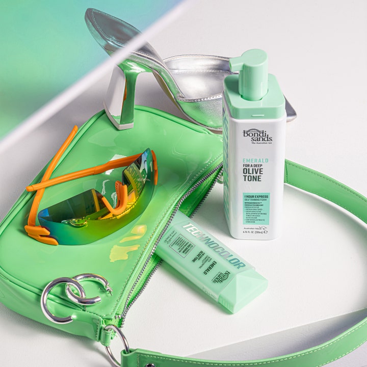 Bondi Sands ansiktsserum Emerald 50 ml ger en olivtonad lyster, ljusgrön tub placerad vid en matchande grön handväska.