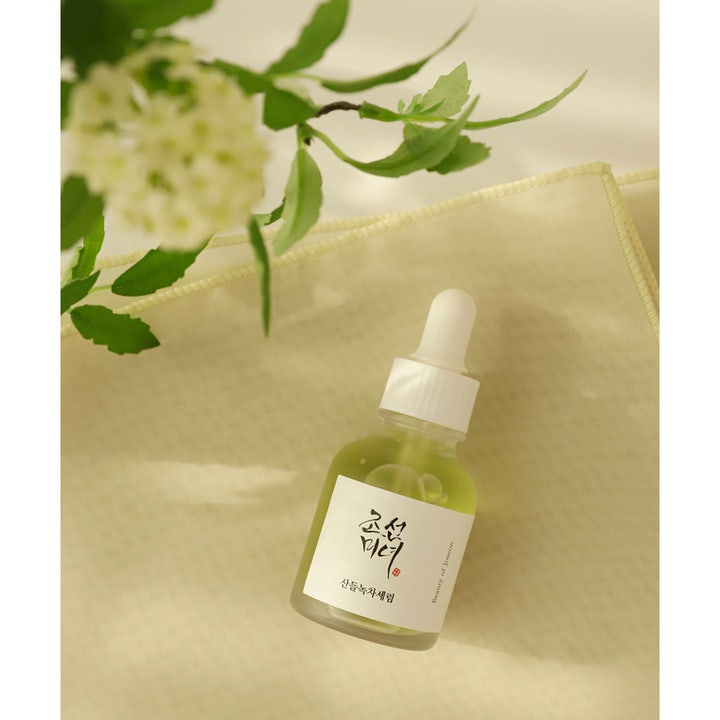 Beauty of Joseon Calming Serum 30 ml anti-inflammatoriskt grönt te serum i glasflaska med pipett intill blommor