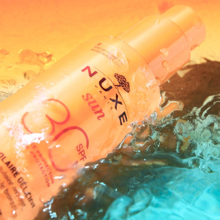 Nuxe Sun Spray SPF30 184 g anti-aging solskydd hydrering i orange flaska omgiven av svalkande vattenstänk