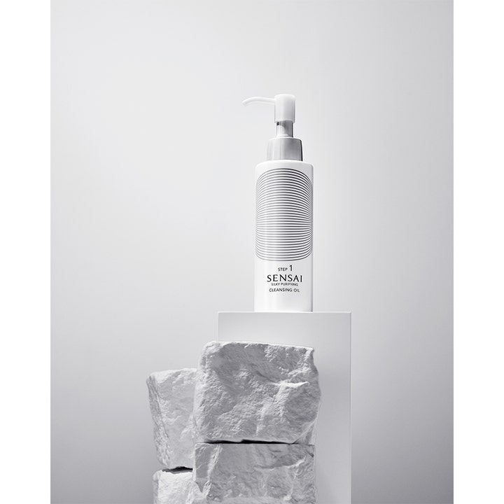 Sensai Silky Purifying Cleansing Oil 150 ml lyxig oljerengöring ansikte i vit pumpflaska på vitt podium med stenar