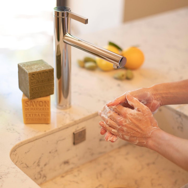 Compagnie de Provence Cube Of Marseille Soap Olive 400 g ekologisk olivtvål som ger mjukt lödder på händer vid en kran.