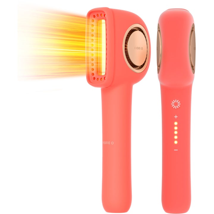 Foreo FAQ 211 handhållen LED-enhet för ljusimpuls hemmabehandling i korallröd design med ett varmt gult sken.