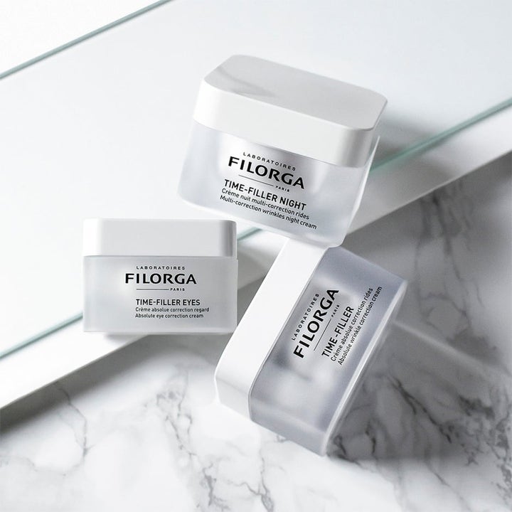 Filorga Anti-Wrinkle Night Time Set anti-age hudvård i frostade glasburkar med vita lock på en marmoryta.