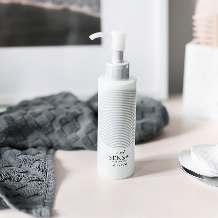 Sensai Silky Purifying Milky Soap 150 ml krämig rengöringsmjölk i vit pumpflaska med silverhals i badrumsmiljö.