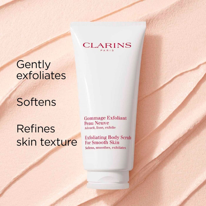 Clarins Exfoliating Body Scrub 200 ml mjukgörande peeling i vit tub mot en bakgrund av rosa krämig textur.