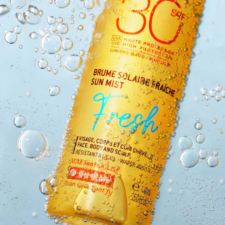 Nuxe Sun Mist Fresh SPF 30 150 ml solspray som ger skydd i en orange flaska nedsänkt i friskt vatten med bubblor