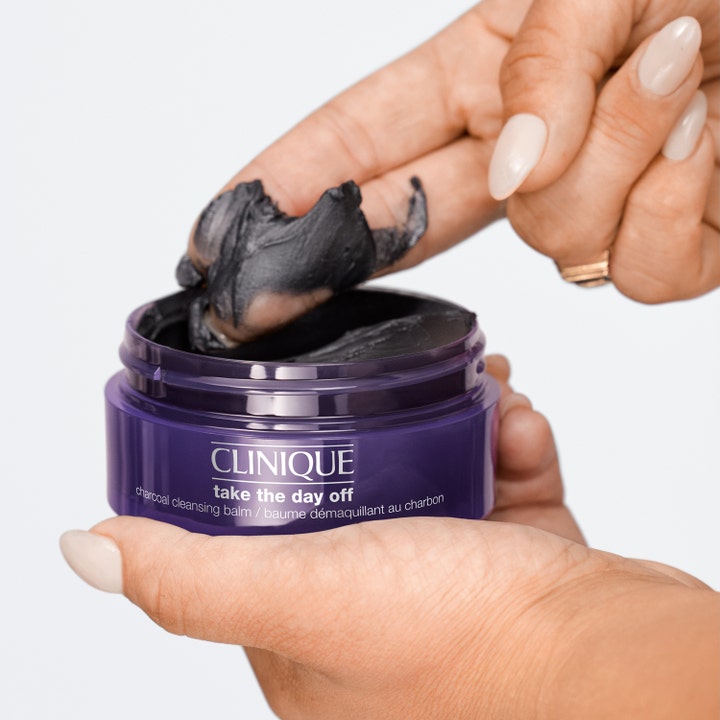 Clinique Take The Day Off Charcoal Balm 125 ml djuprengöring visar en krämig mörkgrå textur som skopas ur lila burk.