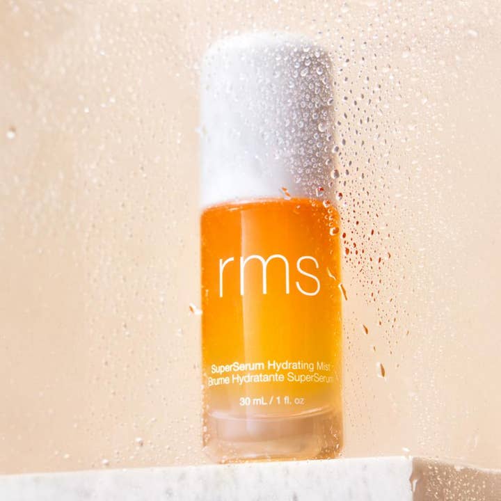 RMS Beauty SuperSerum Hydrating Mist 30 ml återfuktande face mist i orange flaska sedd genom daggiga vattendroppar