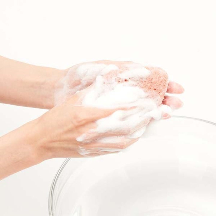 Purito JEJU Volcanic Scoria Konjac Sponge 7 g konjacsvamp som skapar ett vitt lödder i händerna för ansiktsrengöring.