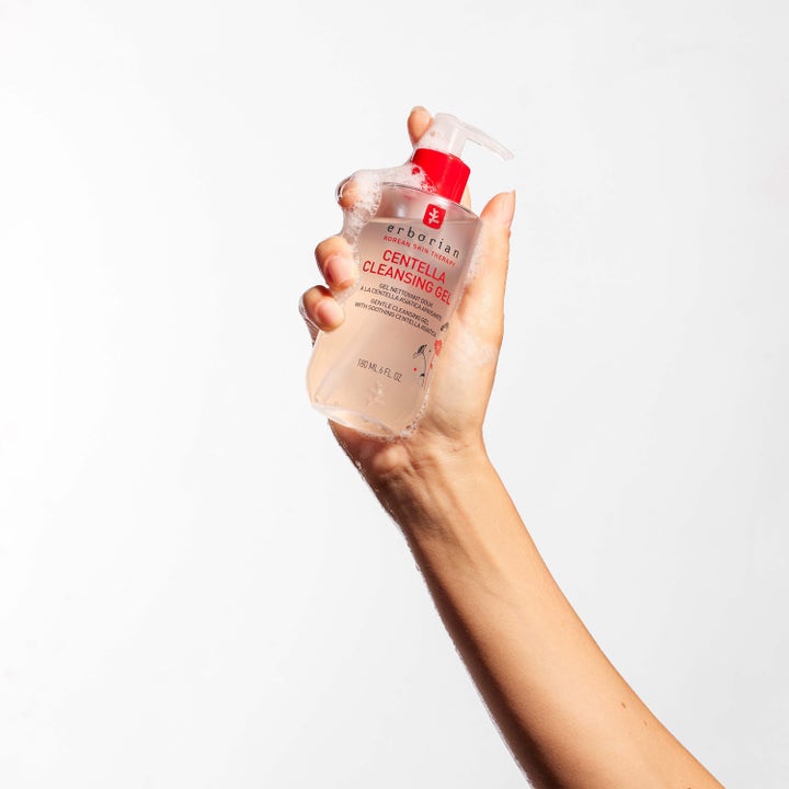 Erborian Centella Cleansing Gel 180 ml lugnande ansiktsrengöring i en hand med röd pumpflaska och vitt lödder