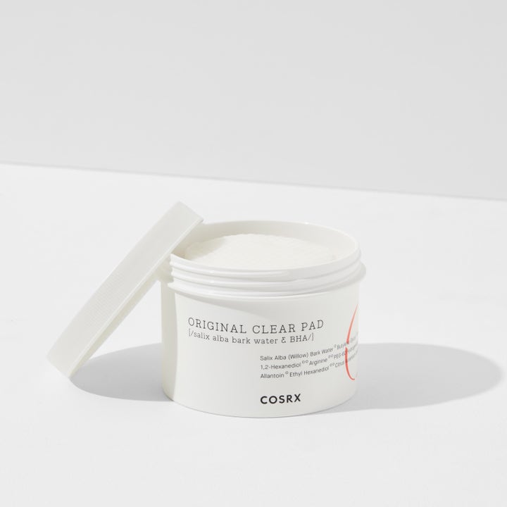COSRX One Step Original Clear Pad 70 st bha exfoliering pads i en öppen vit burk med vita pads och ett lutat lock.