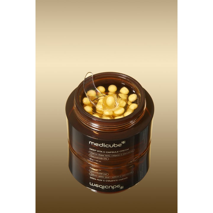 Medicube Deep Vita C Capsule Cream 55 g lystergivande ansiktskräm med gula kapslar i gel och en genomskinlig spatel.