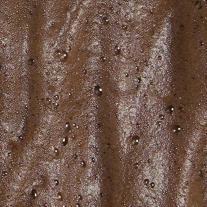 Bronza Bronzing Mousse Deep Bronze 200 ml brun utan sol mousse för ansikte och kropp med bubblig mörkbrun textur.