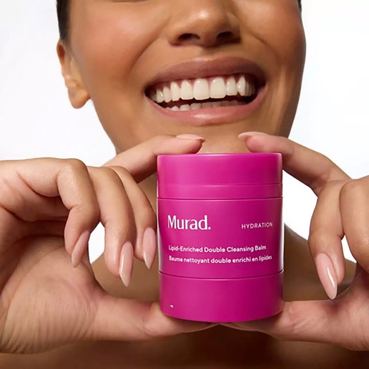 Murad Lipid-Enriched Double Cleansing Balm 50 ml återfuktande rengöringsbalsam i en rosa burk som hålls av en kvinna