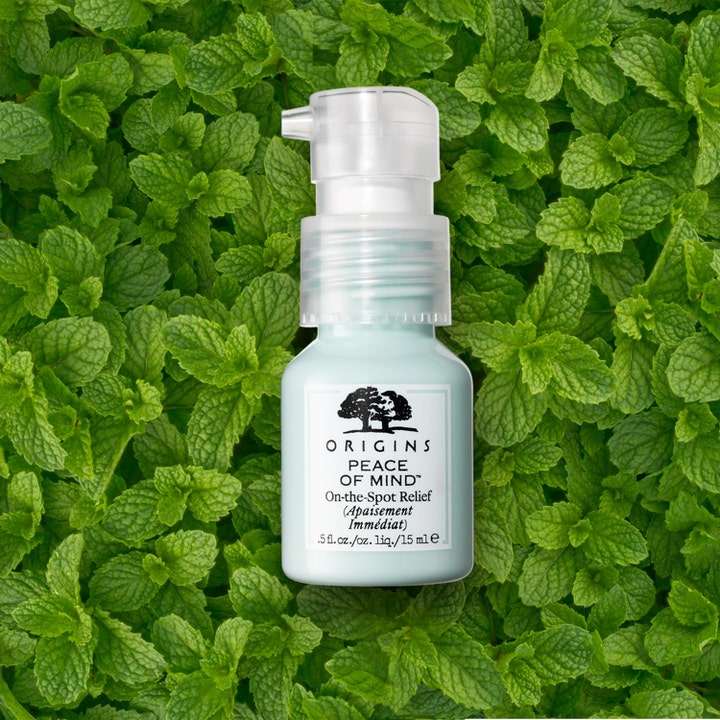 Origins Peace Of Mind 15 ml punktbehandling ger avslappning i en ljusblå flaska placerad på gröna myntablad