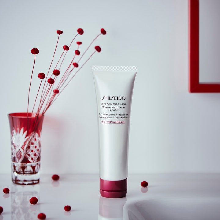 Shiseido Defend Deep Cleansing Foam 125 ml djuprengöring för aknebenägen hy i vit tub med rött lock bredvid en röd vas.
