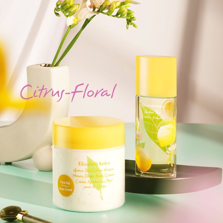 Elizabeth Arden Green Tea Citron Freesia Body Cream 500 ml i burk bredvid parfym i en blommig miljö.