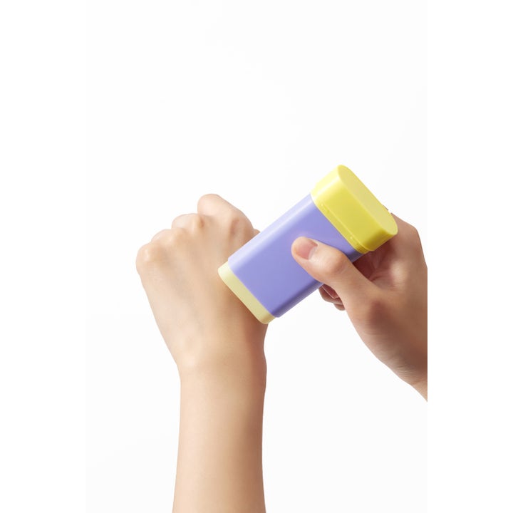 By Wishtrend Pore Smoothing Bakuchiol Sun Stick 18 g porutjämnande solstick i lila hylsa som appliceras på en hand.