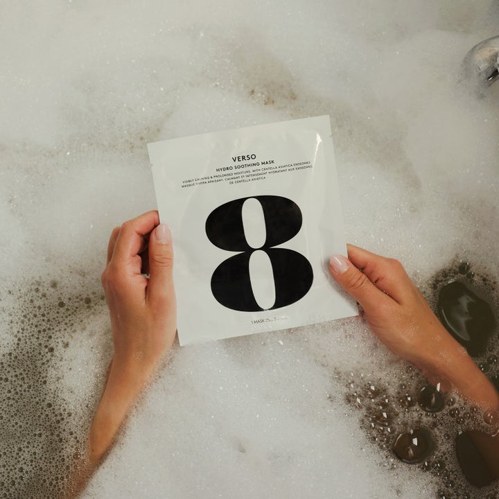 Verso N°8 Hydro Soothing Mask 1 st återfuktande ansiktsmask i vit sachet som hålls över ett bubbelbad.