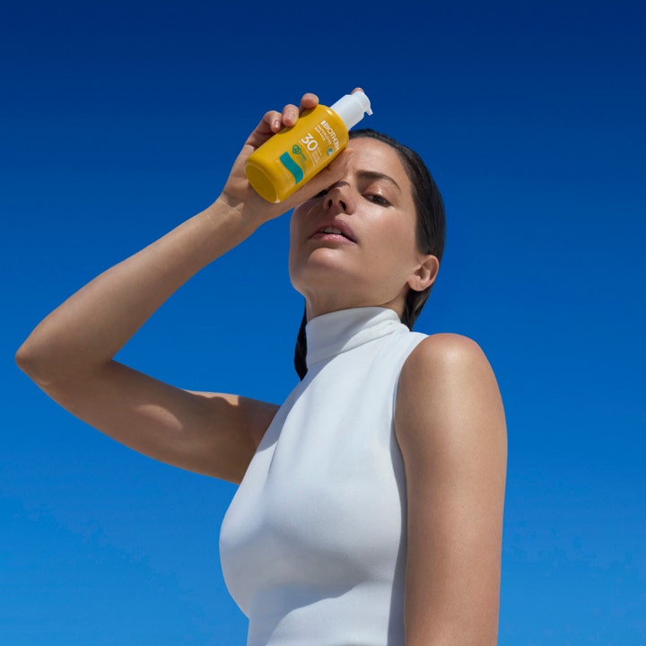Biotherm Waterlover Sun Milk 200 ml solskyddsfaktor 30 miljövänlig solmjölk hålls av en kvinna mot blå himmel