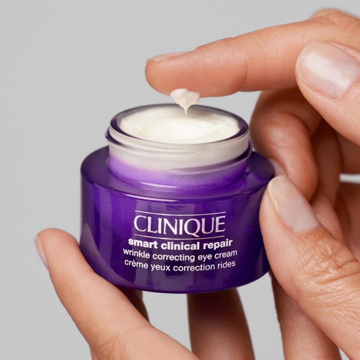 Clinique Smart Clinical Repair 15 ml kliniskt testad ögonkräm i lila burk med krämig vit textur på ett finger.