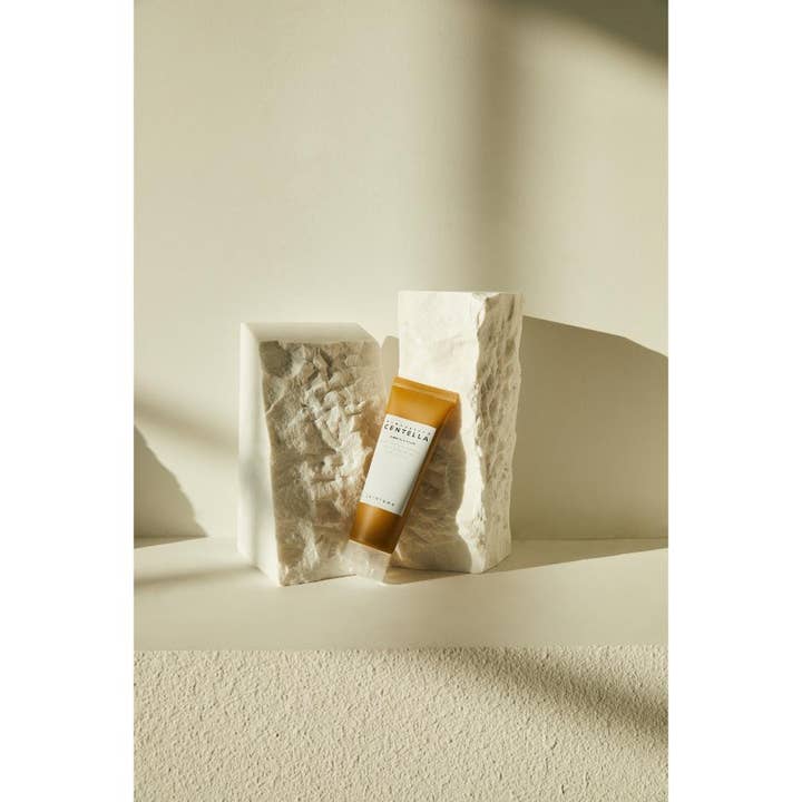 SKIN1004 Madagascar Centella Ampoule Foam 125 ml lugnande ansiktsskum i bärnstensfärgad tub mot vita stenblock