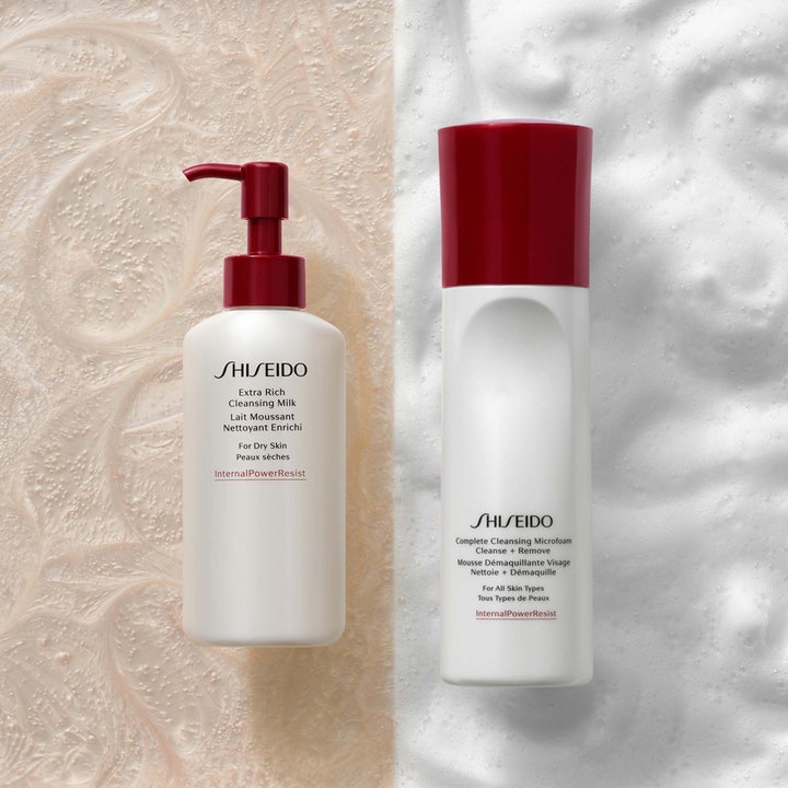 Shiseido Complete Cleansing Microfoam 180 ml rengöringsmousse ansikte i vit flaska med rött lock mot en vit skummig yta.