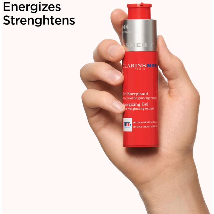 Clarins Men Energizing Gel 50 ml röd ginseng ansiktsgel i röd flaska som hålls av en hand.