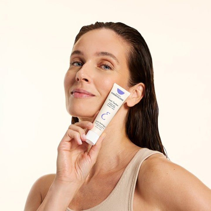 Embryolisse Brightening Dark Spot Night Peeling 40 ml nattkräm mot mörka fläckar i vit tub som hålls av en leende kvinna.