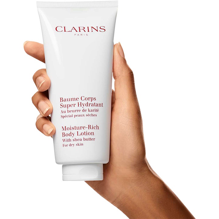 Clarins Moisture-Rich Body Lotion 200 ml återfuktande kroppslotion med sheasmör i vit tub som hålls i en hand.