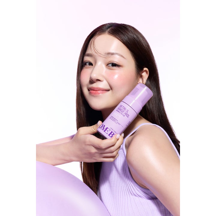 Some By Mi Retinol Bakuchiol Bubble Toner 100 ml i lila flaska som hålls av en kvinna med lyster i huden