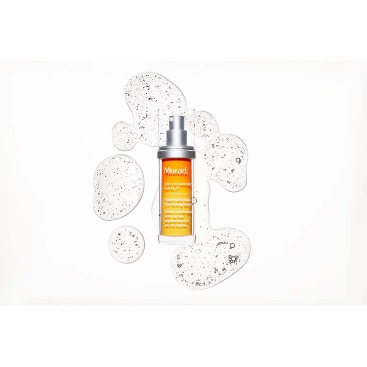 Murad Spot Corrector 80 ml pigmentfläcks-behandling mot solskador i pumpflaska omgiven av textur med mörka korn